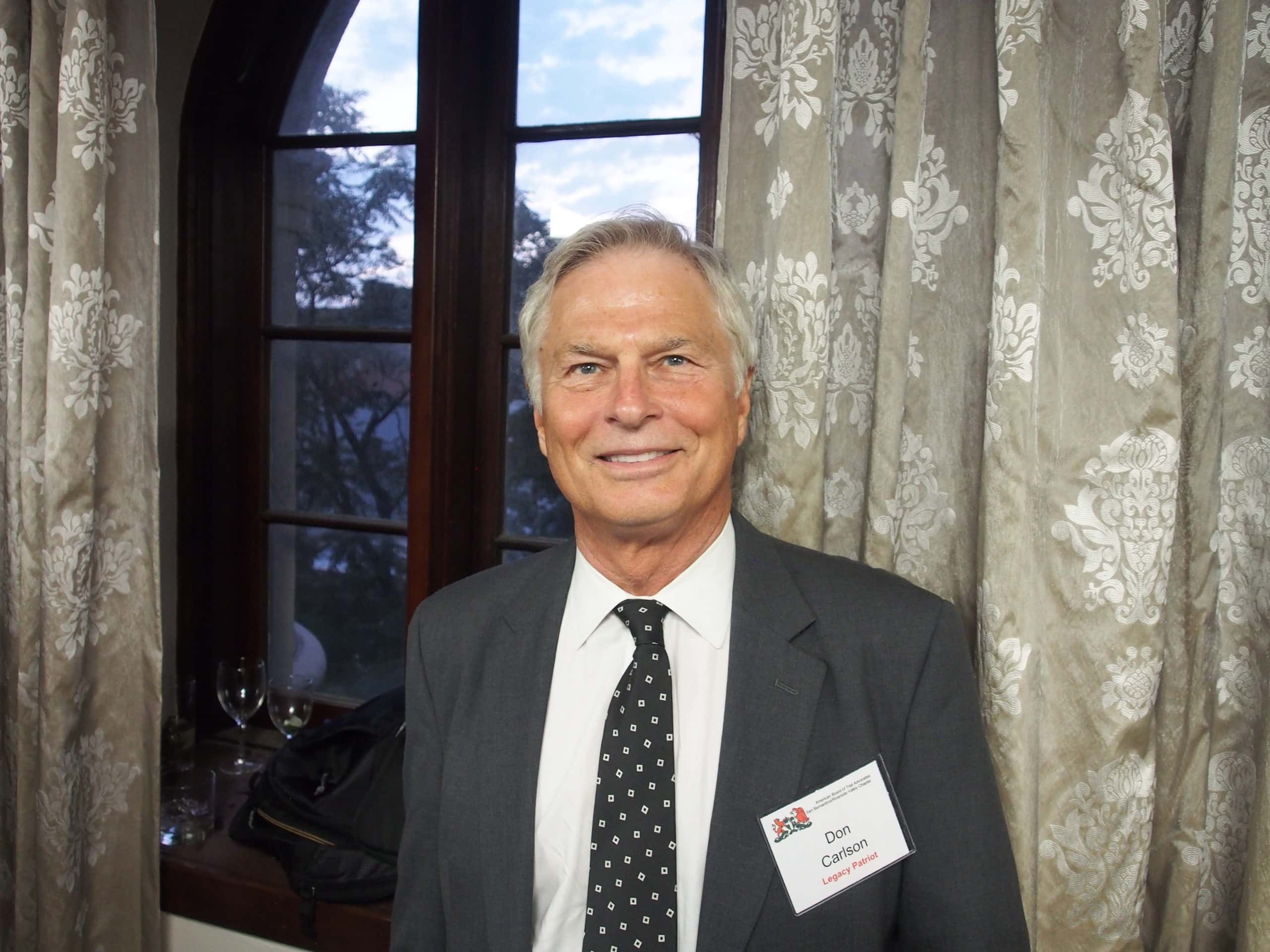 Man in suit with black tie with white squares.