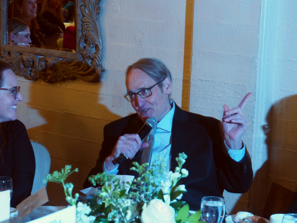 Man, seated, talks into microphone