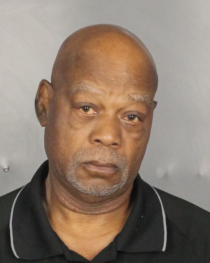 Retired truck driver Douglas Thomas, black, bald, grey hair, and a goatee, in his booking photo, wearing a black polo.