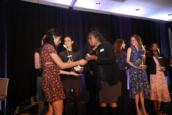high schoolers receive trophy on stage
