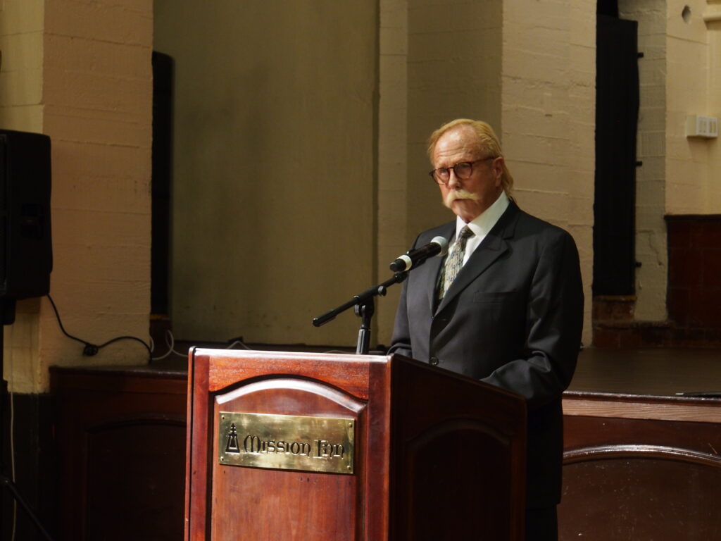 Man stands behind microphone at lectern